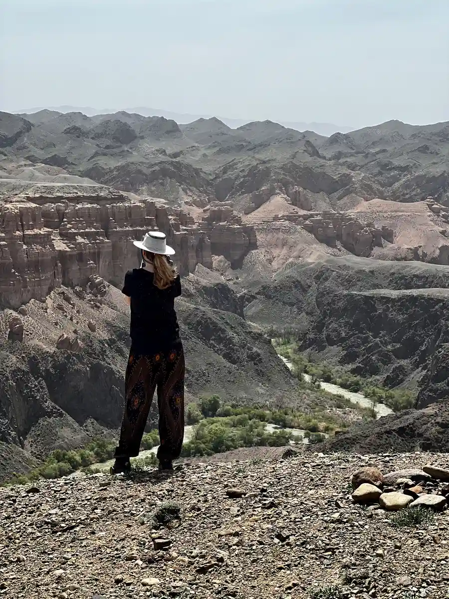 Woman in a sun hat photographing the canyon from a lookout point above the Charyn River